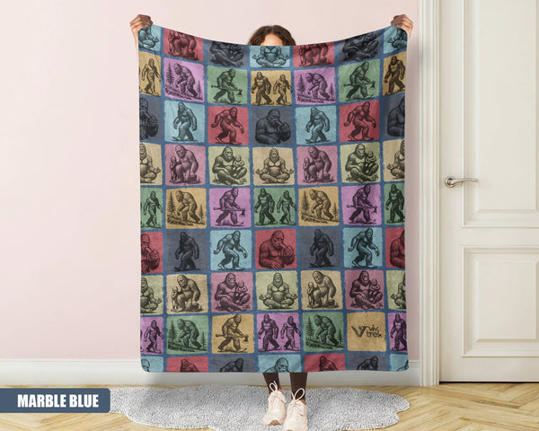 Person holding a colorful blanket with a pattern of Bigfoot in a room.