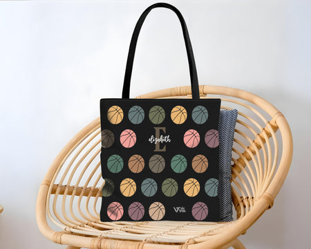 Black tote bag with colorful basketball pattern on a wicker chair