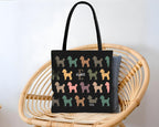 Black tote bag with colorful dog pattern and initial name text