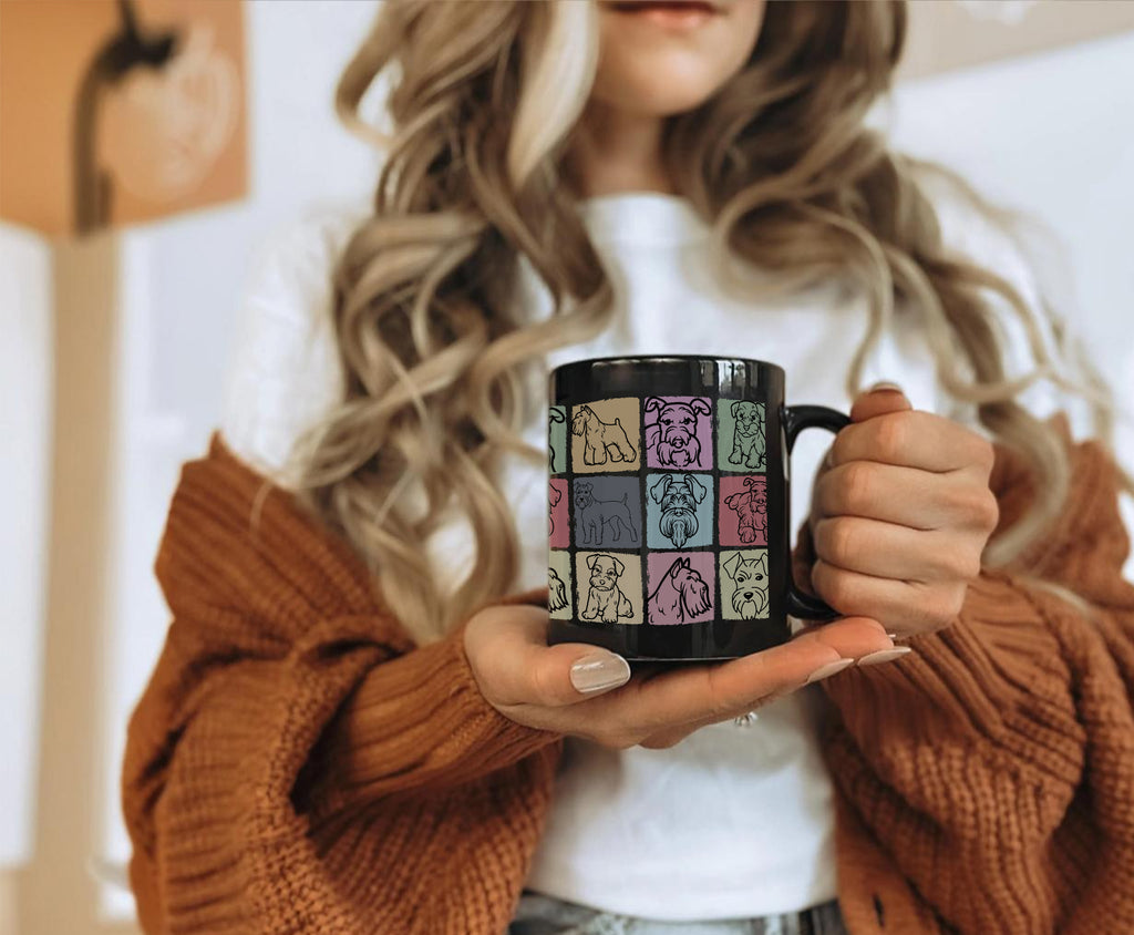 Person holding a black and white mug with colorful dog pattern