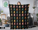 Person holding a black blanket with colorful bigfoot pattern in a room.