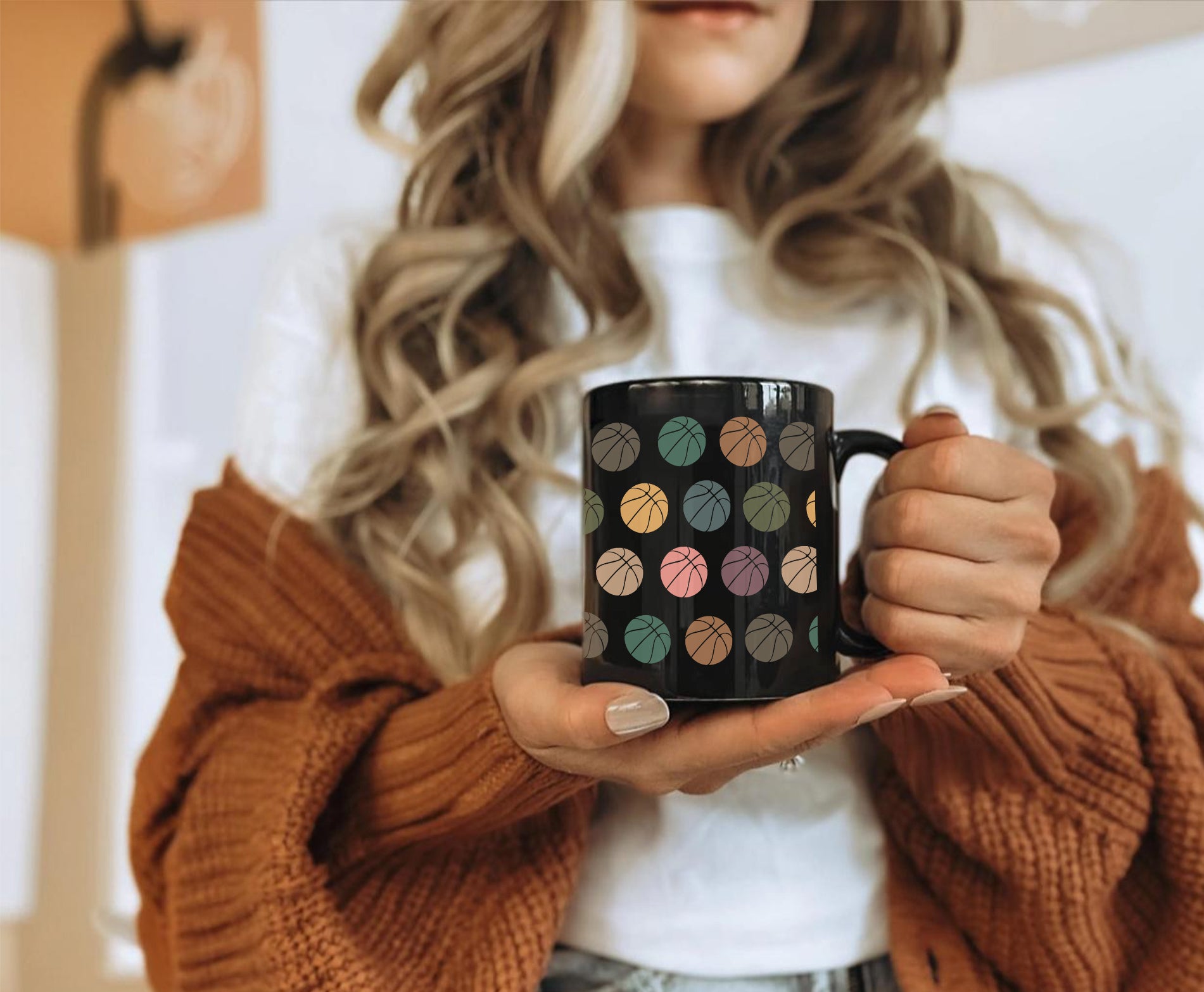 Person holding a black mug with colorful basketball design.