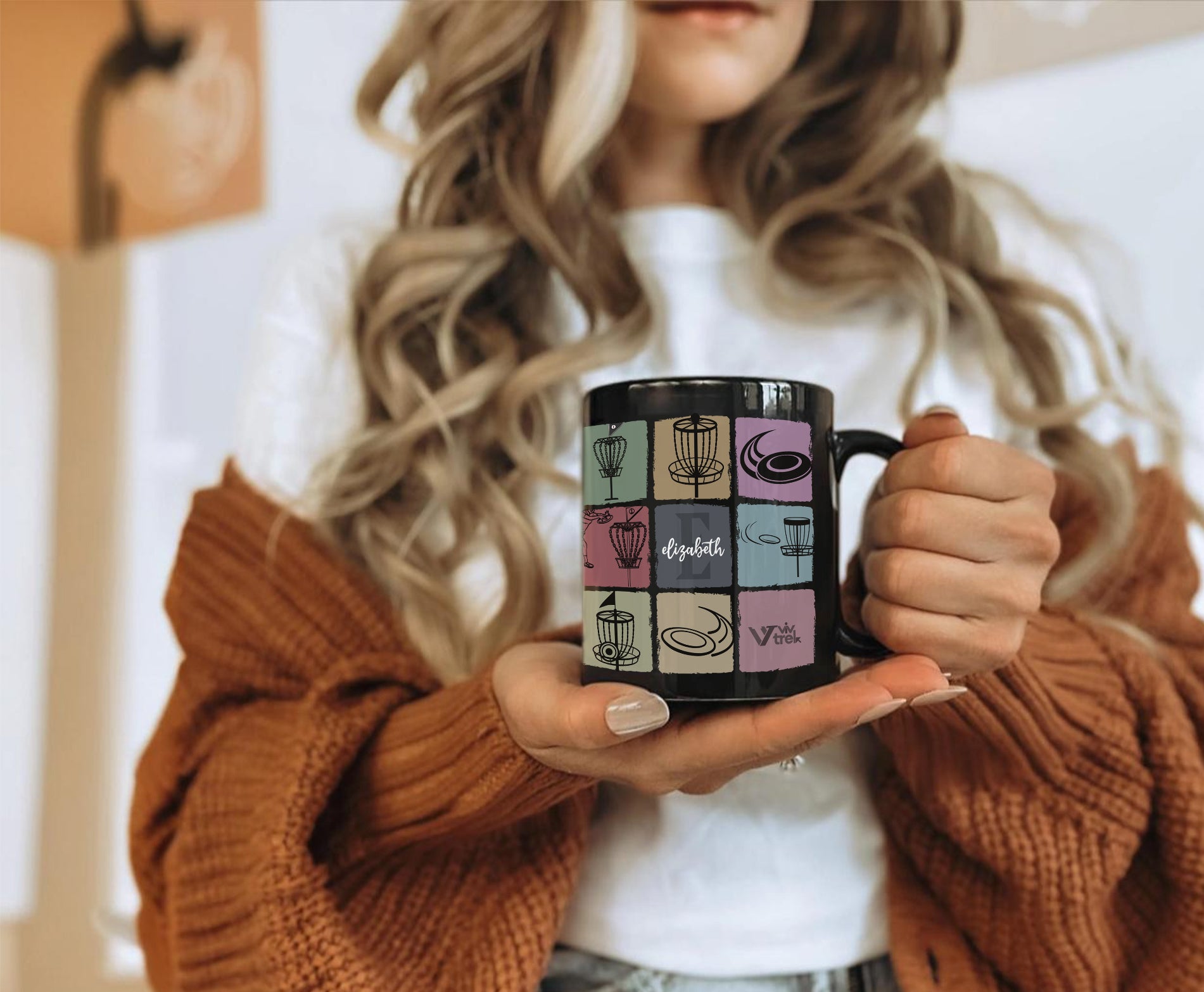 Person holding a black mug with colorful designs and name text