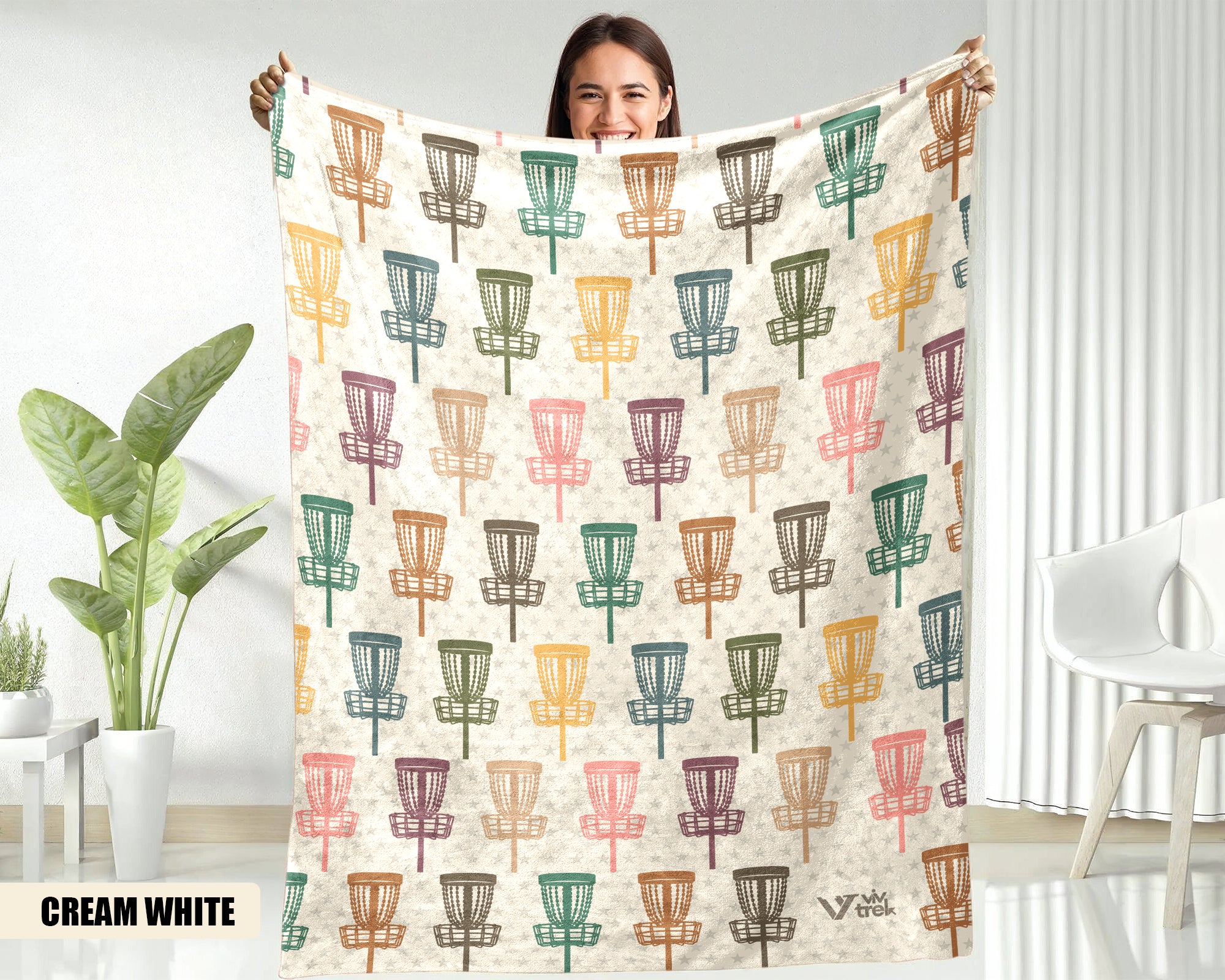 Person holding a blanket with disc golf disc pattern in a room with plants and furniture.