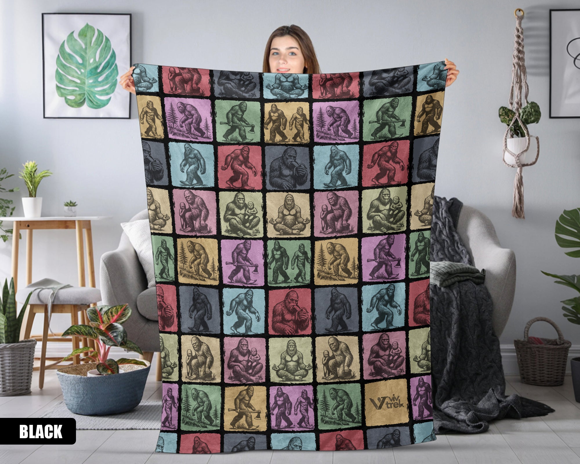 Person holding a colorful Bigfoot patterned blanket in a living room.