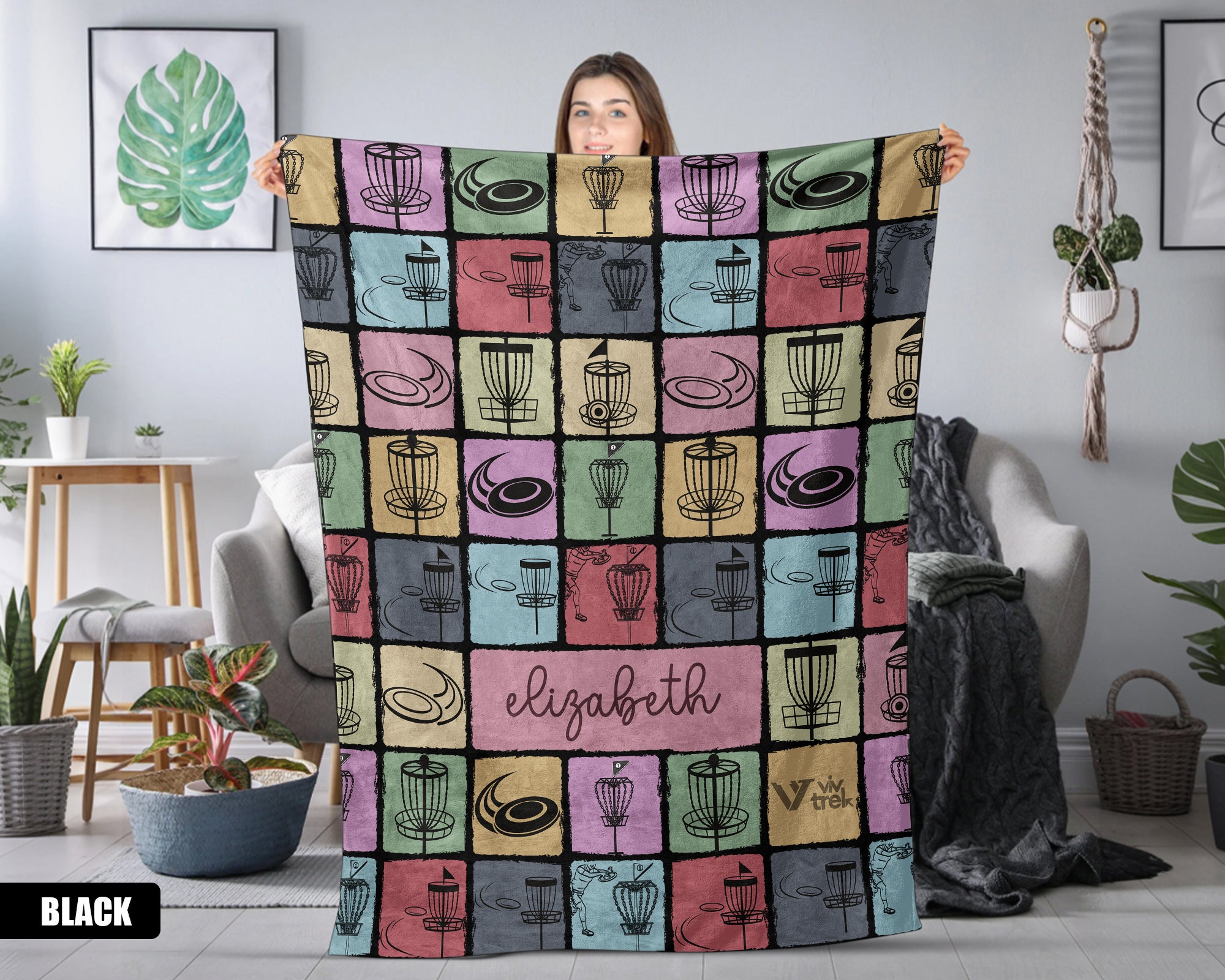 Person holding a colorful patterned blanket with name text printed on it in a room setting.