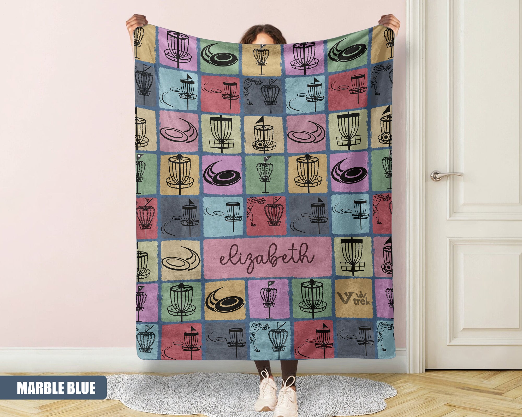 Person holding a colorful patterned disk golf blanket with name text printed on it.