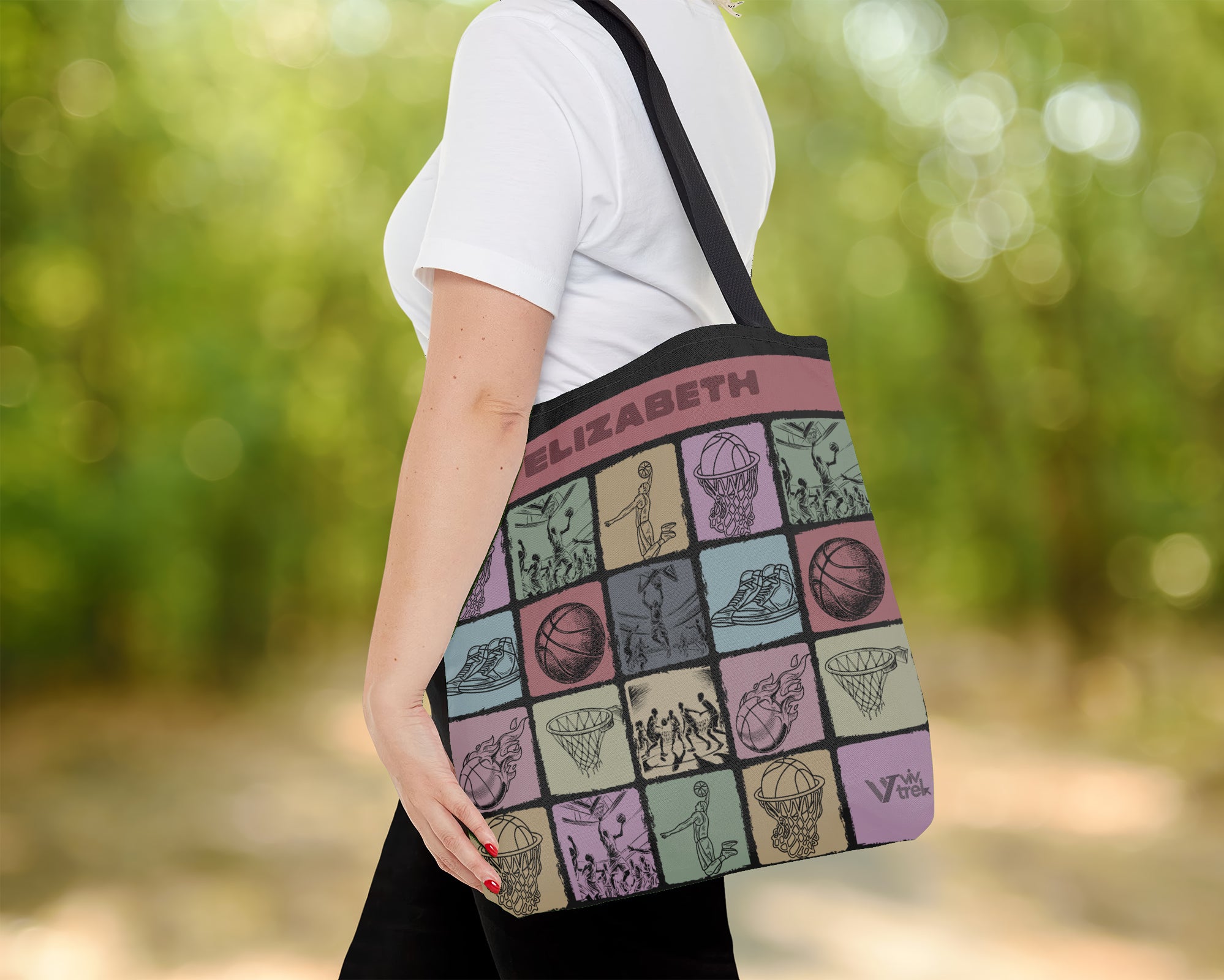 Person holding a colorful tote bag with various basketball designs and text outdoors.