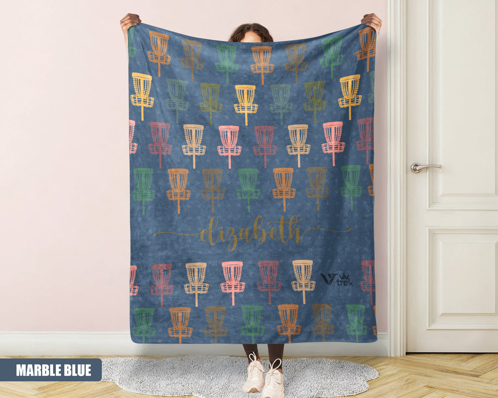 Person holding a decorative blanket with disc golf basket pattern and name text.