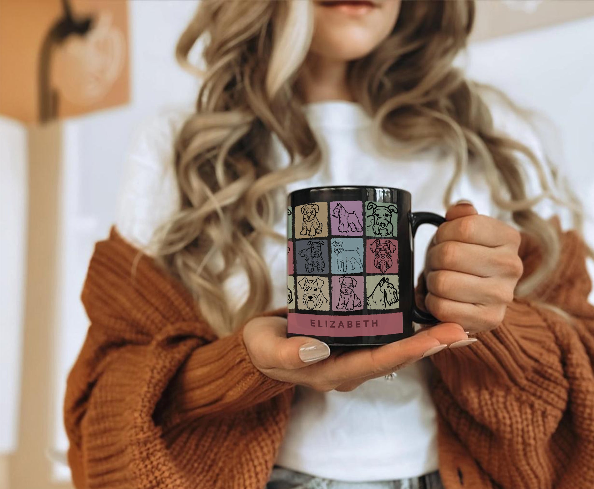 Person holding a mug with colorful design and name text on a blurred background