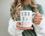 Person holding a mug with colorful designs and the letter text on it.