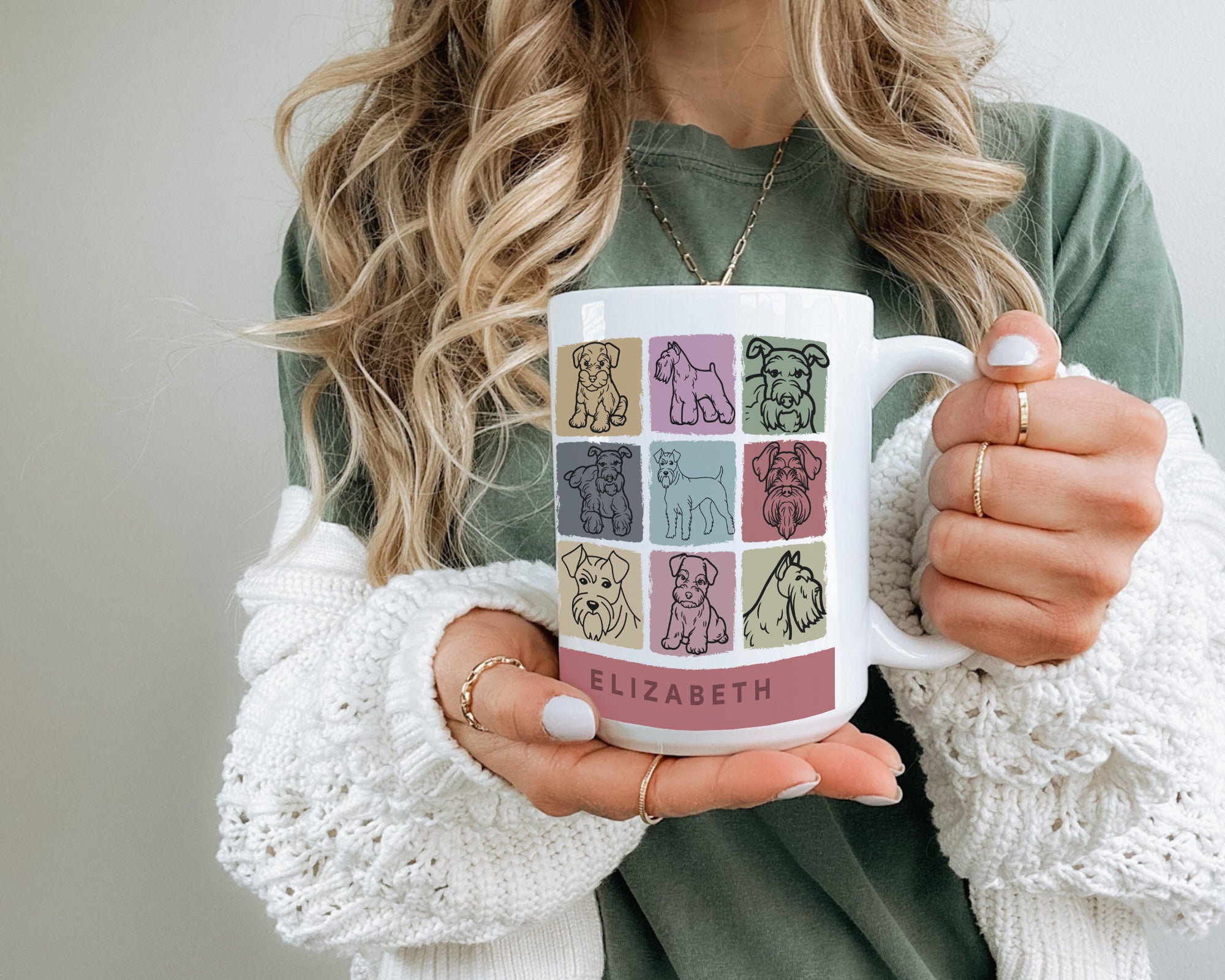 Person holding a mug with dog illustrations and the initial name on it.