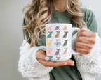 Person holding a mug with dog pattern and initial name text