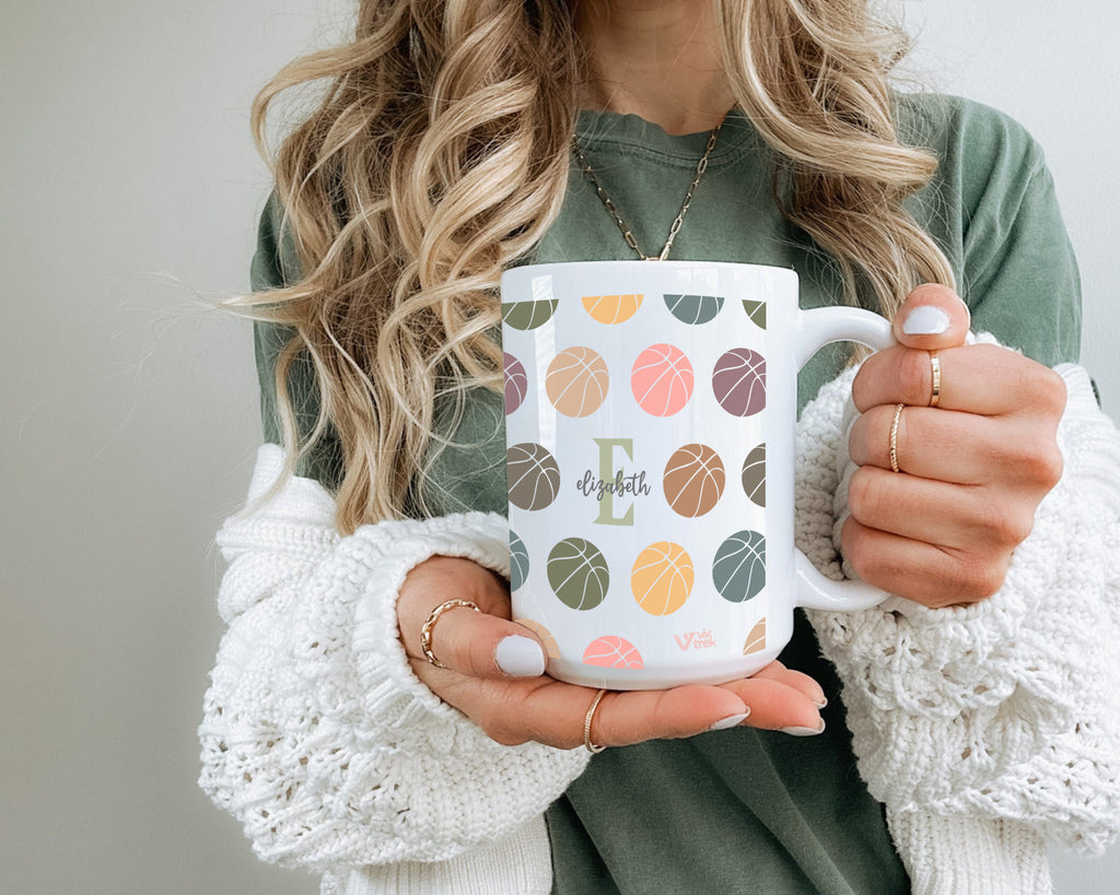 Person holding a mug with leaf pattern and name Text.