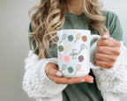 Person holding a mug with tennis racket design and letter.