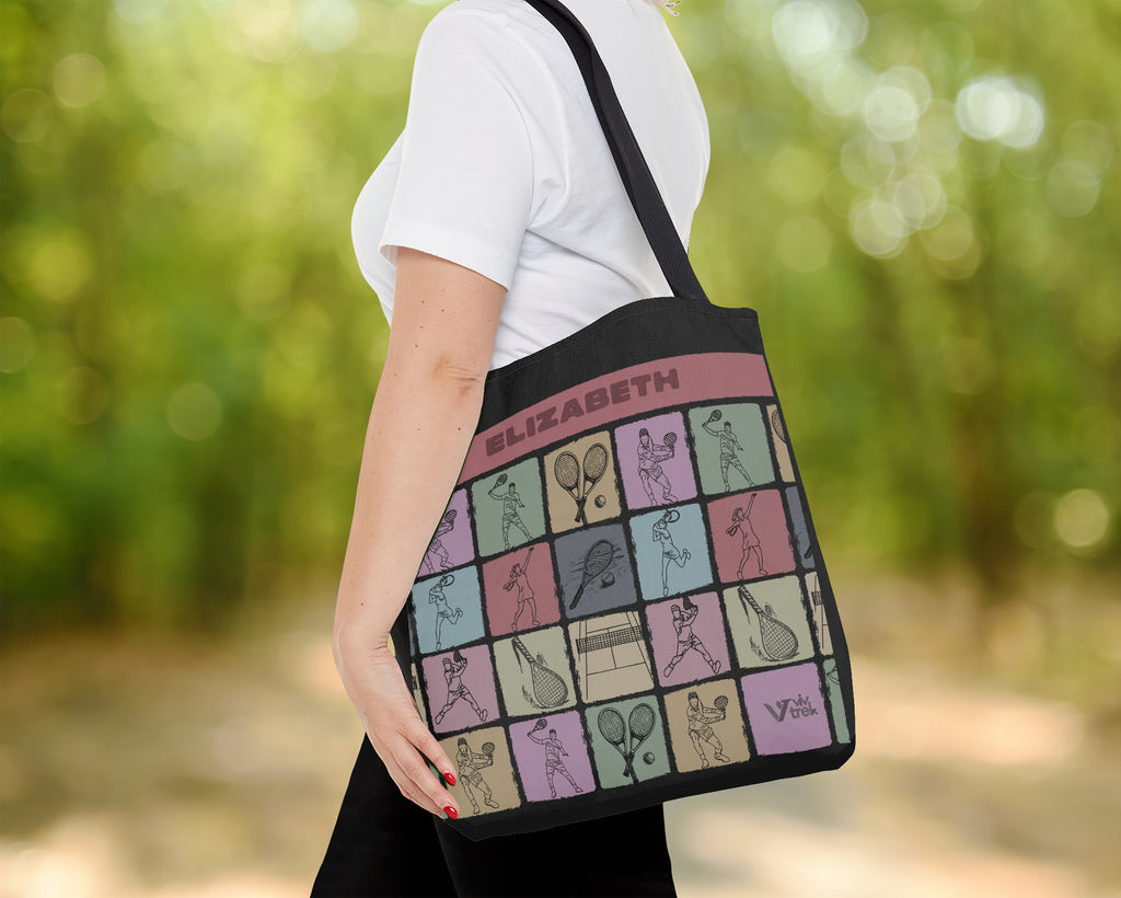 Person holding a tote bag with a pattern of tennis-themed illustrations and the name on a blurred green background.