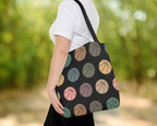 Person holding a tote bag with colorful basketball pattern against a blurred green background
