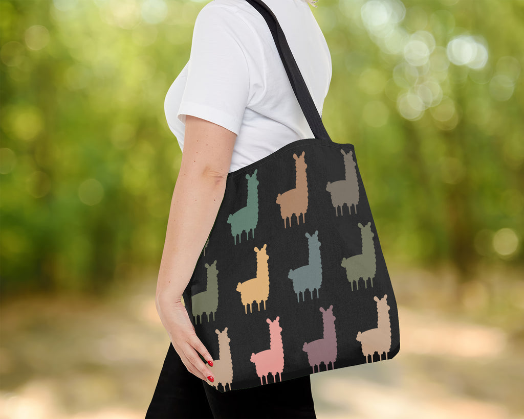 Person holding a tote bag with llama pattern outdoors